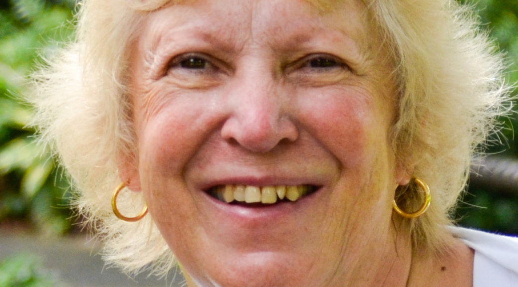 Smiling elderly woman with blonde hair outdoors.